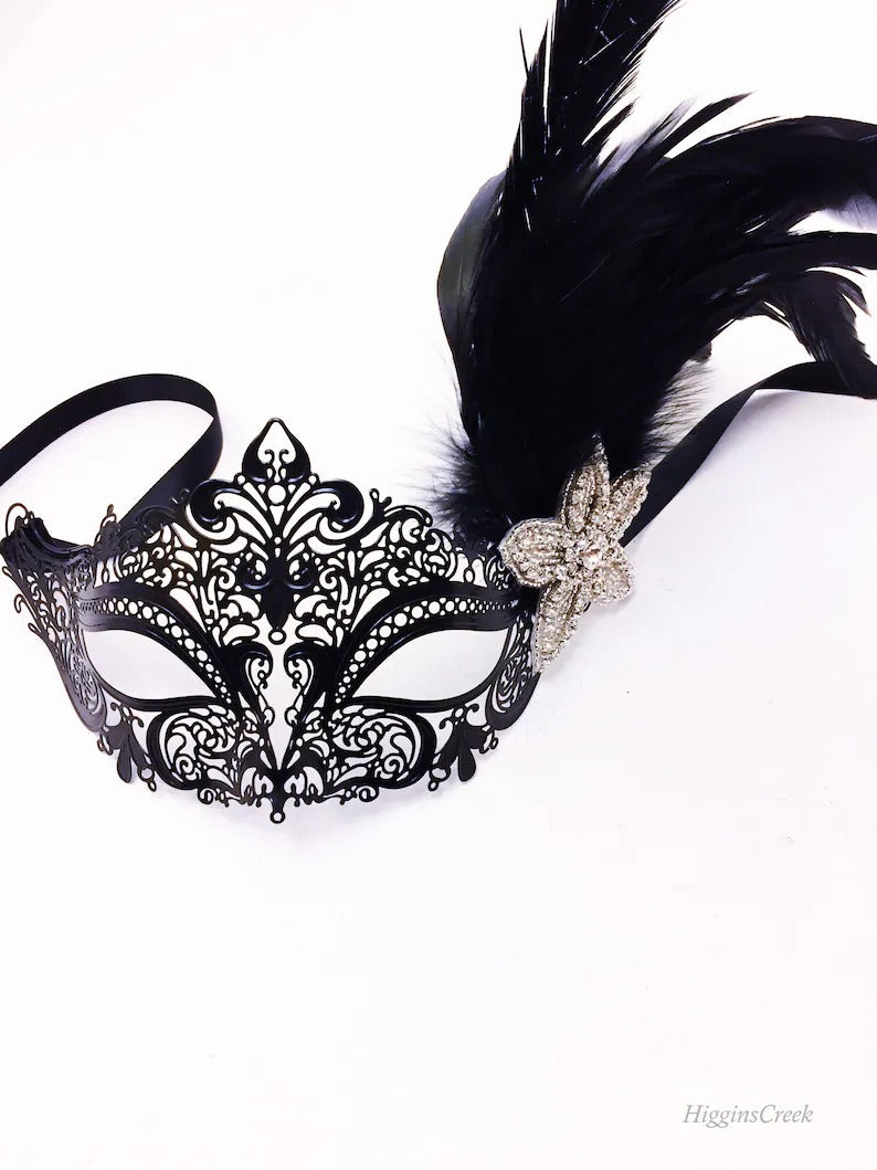 Ornate black masquerade mask with feather accents and rhinestone flower, perfect for prom, masquerade ball, or carnival event.