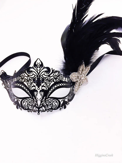 Ornate black masquerade mask with feather accents and rhinestone flower, perfect for prom, masquerade ball, or carnival event.