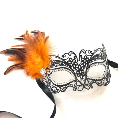 Elegant black filigree masquerade mask with bright orange feathers and rhinestone details.