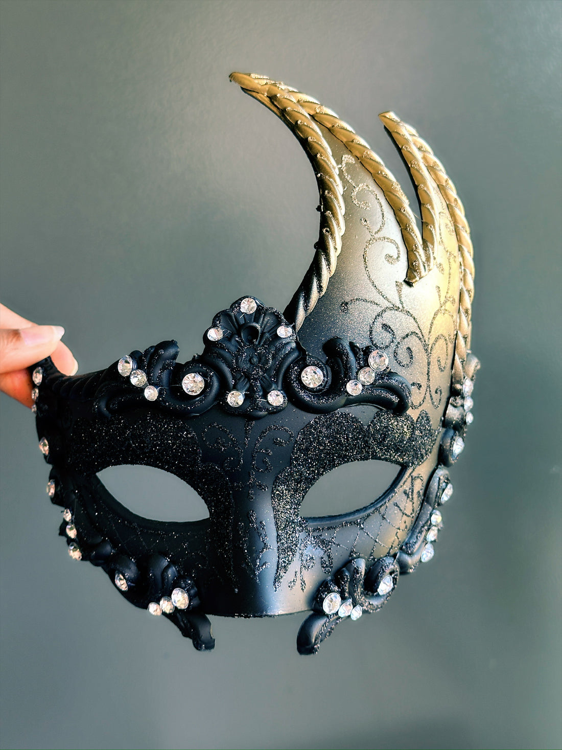 Black and gold horn masquerade mask with rhinestones and glitter details, designed for Venetian balls, parties, or fantasy costumes.