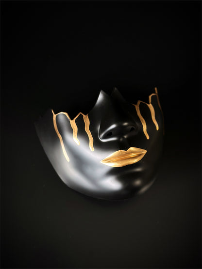 Black mask with gold accents, featuring minimalist art deco design

