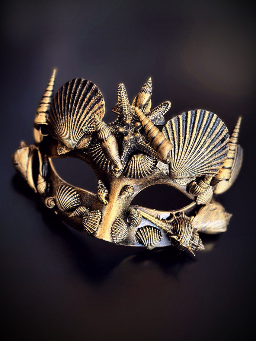 Black and gold masquerade mask decorated with seashells and ocean-inspired starfish details.