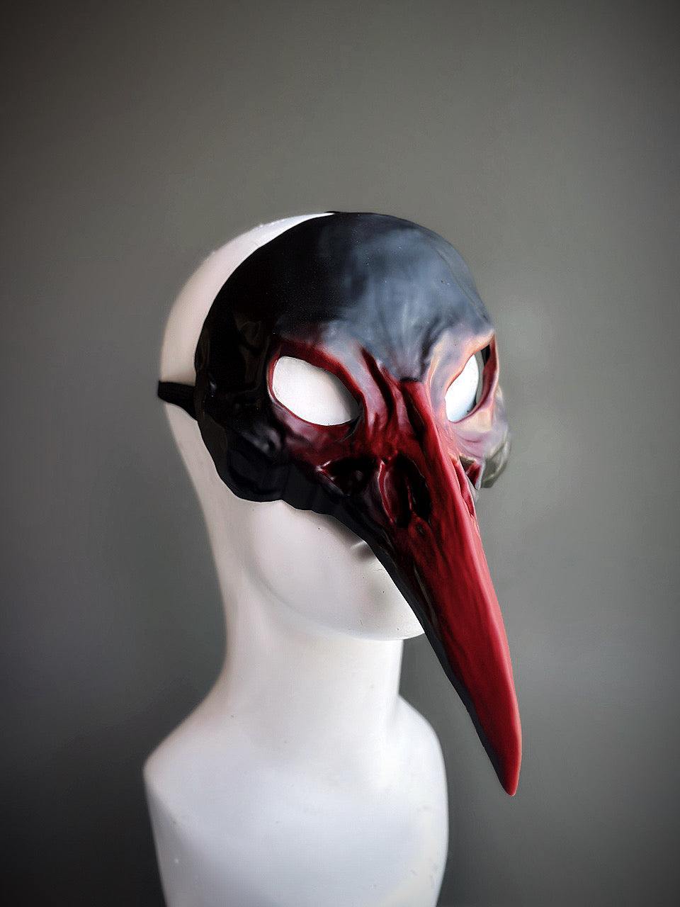 Black and red bird mask featuring a sleek black upper and deep red detailing, ideal for masquerades and theatrical events.

