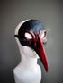 Black and red bird mask featuring a sleek black upper and deep red detailing, ideal for masquerades and theatrical events.

