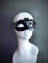 Black steampunk masquerade mask for women with intricate gear details and industrial-inspired design, displayed on a mannequin head.

