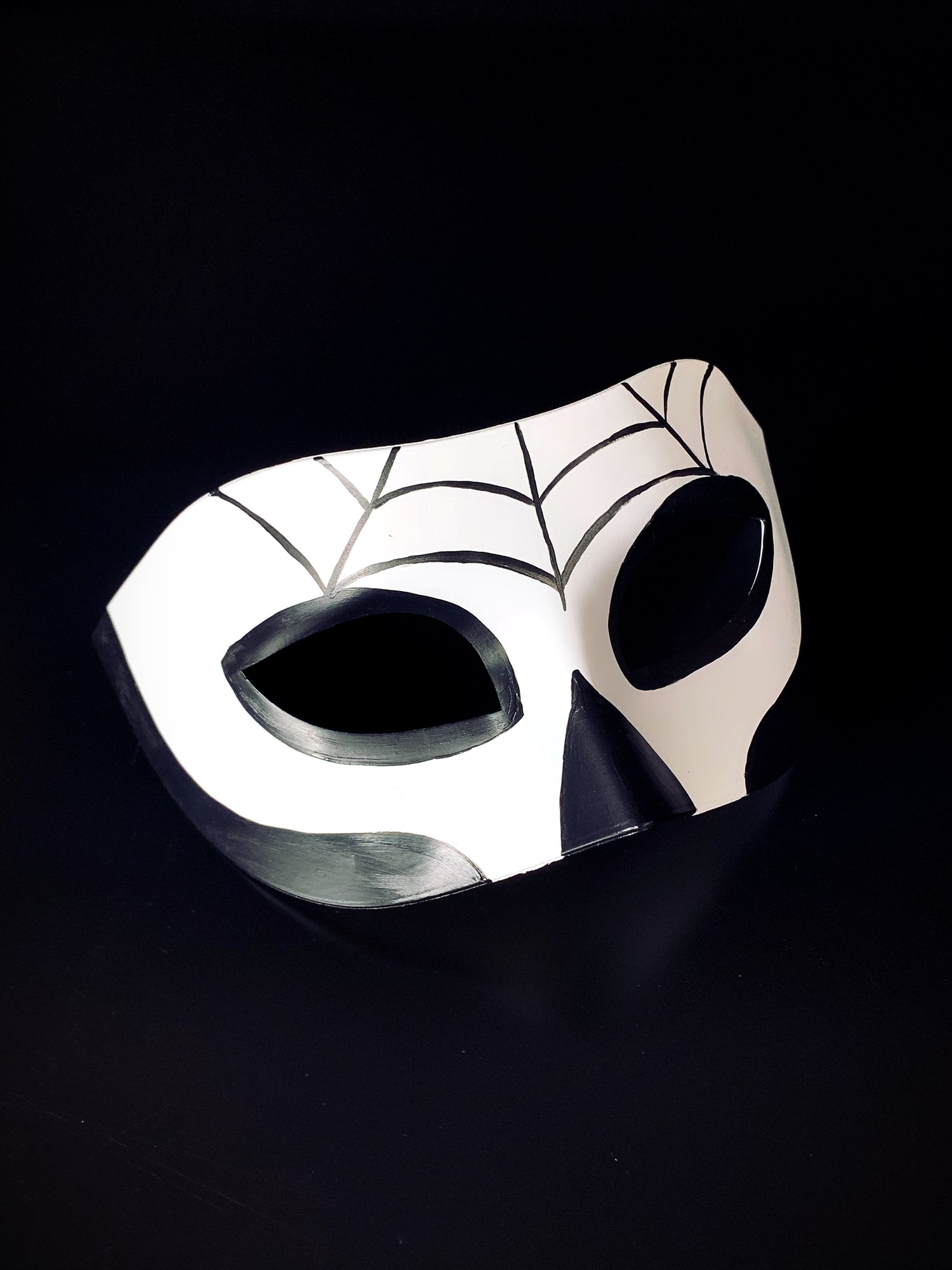 Black and white mask with spiderweb design, perfect for Dia de los Muertos celebrations


