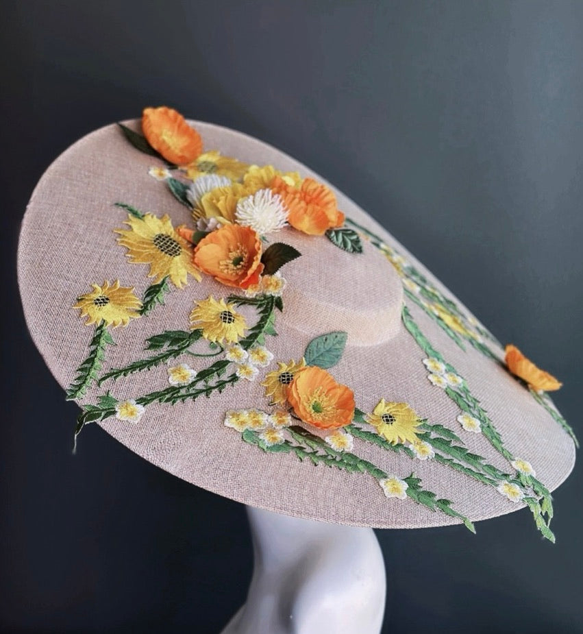 Blush beige oversized floral Derby hat with embroidered sunflower detailing and botanical embellishments on structured saucer-style sinamay brim