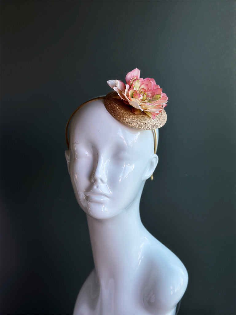 Blush pink floral piece on a beige sinamay hat base fixed on a matching headband