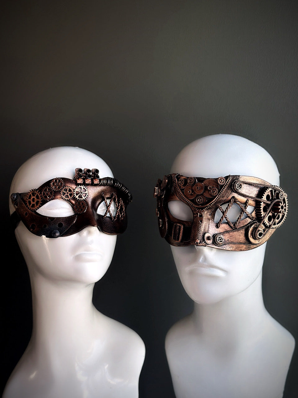 Bronze steampunk couples masquerade mask set with intricate gear detailing and industrial-inspired accents, displayed on mannequin heads.

