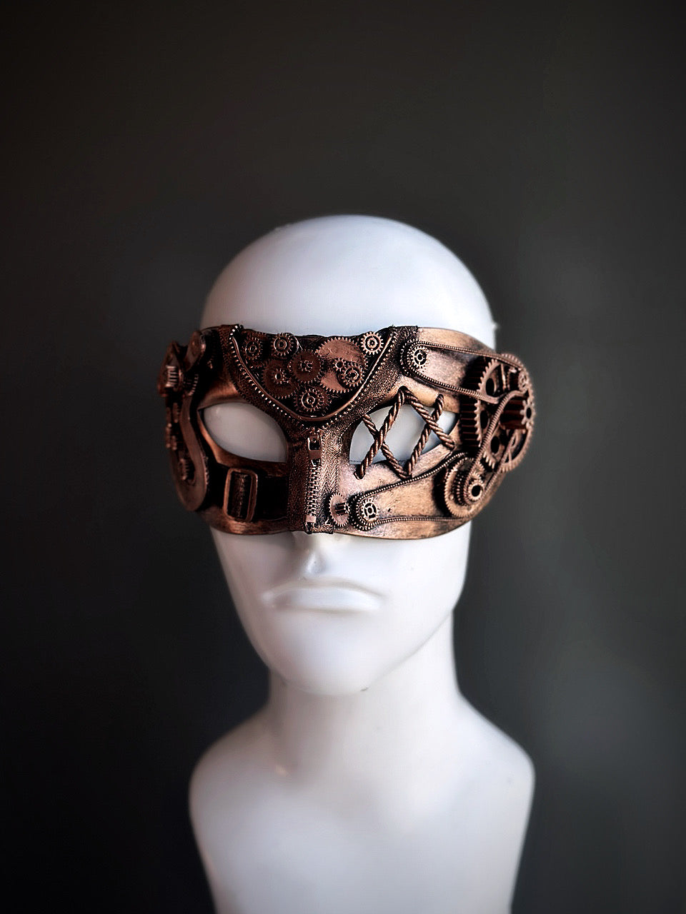 Bronze steampunk masquerade mask with detailed gears and mechanical accents displayed on a mannequin head.

