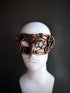 Bronze steampunk masquerade mask with detailed gears and mechanical accents displayed on a mannequin head.

