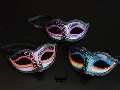 Bulk black Venetian masquerade masks with rainbow glitter bands, colorful filigree detailing, braided trim, and sparkling accents for Pride celebrations and masquerade events.