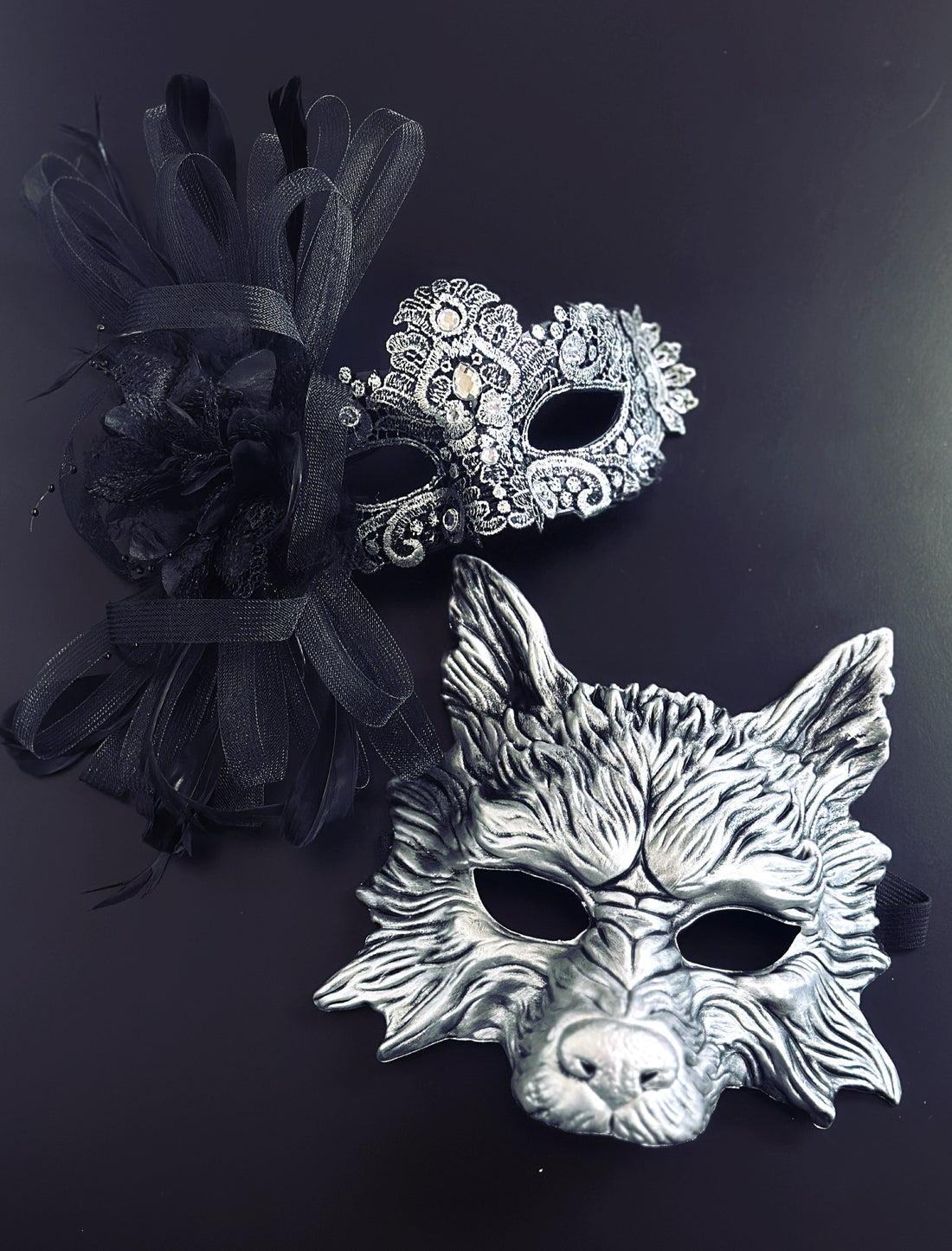 Silver lace womens masquerade mask with black feathers, paired with a black silver men&