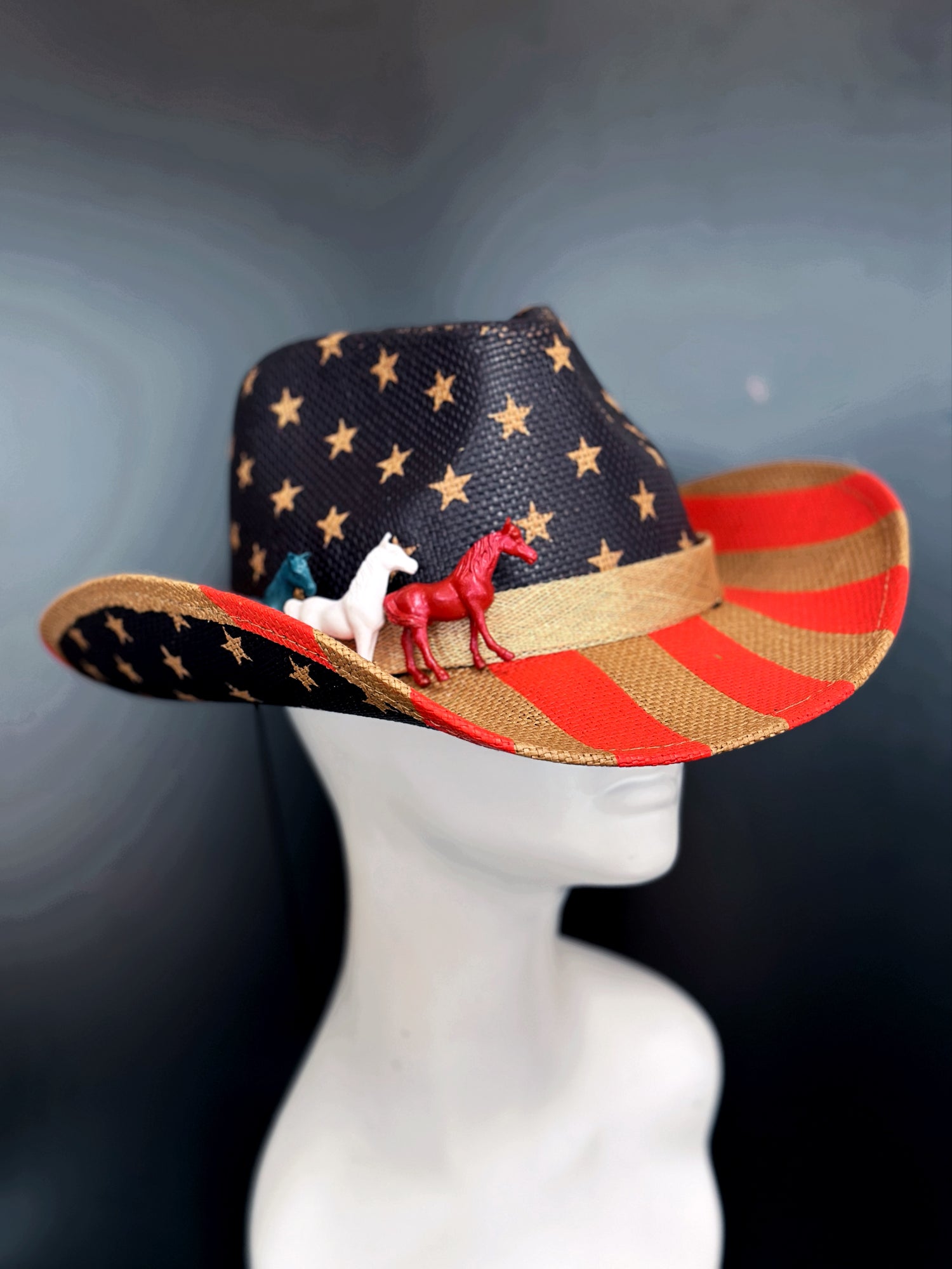 Cowboy hat with a USA flag design featuring stars, stripes, and painted horses in white blue and red.