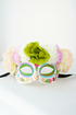 Sugar skull mask with pastel flower crown in green, pink, and cream for Dia de los Muertos.