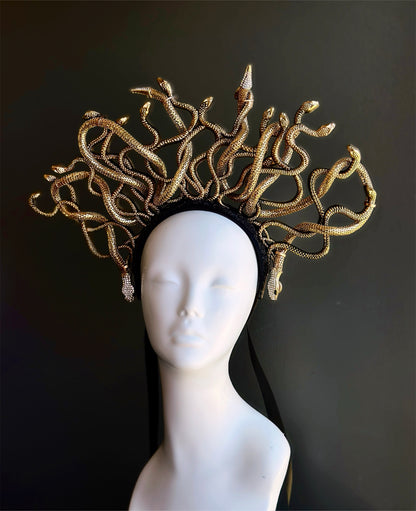 Gold snake headpiece on a mannequin head against a black background