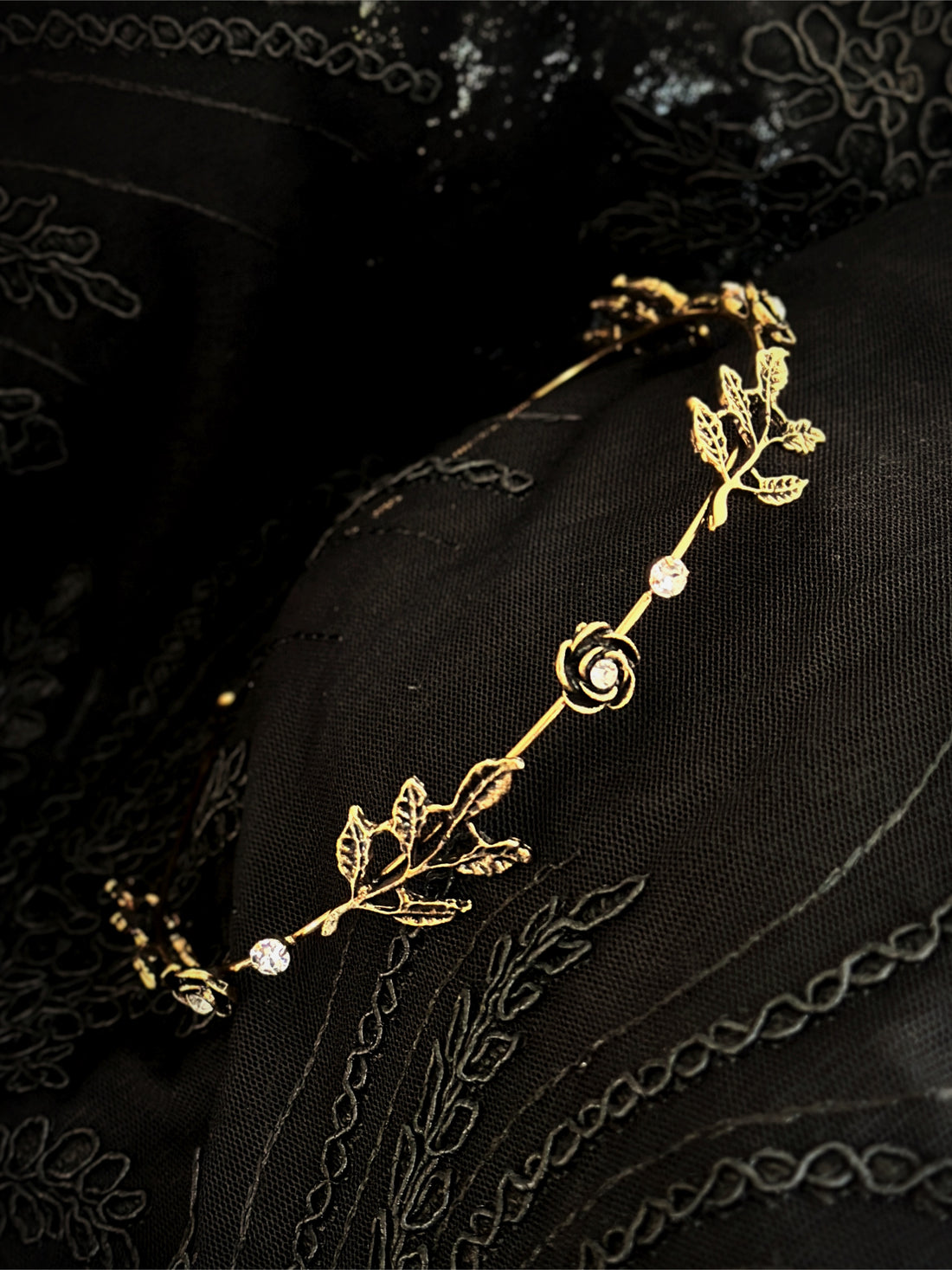 Gold rose vine headband with crystals on black fabric background