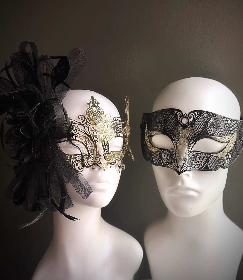 Couples masquerade masks in black and gold with baroque detailing, one with tulle and feathers and the other with filigree scrollwork

