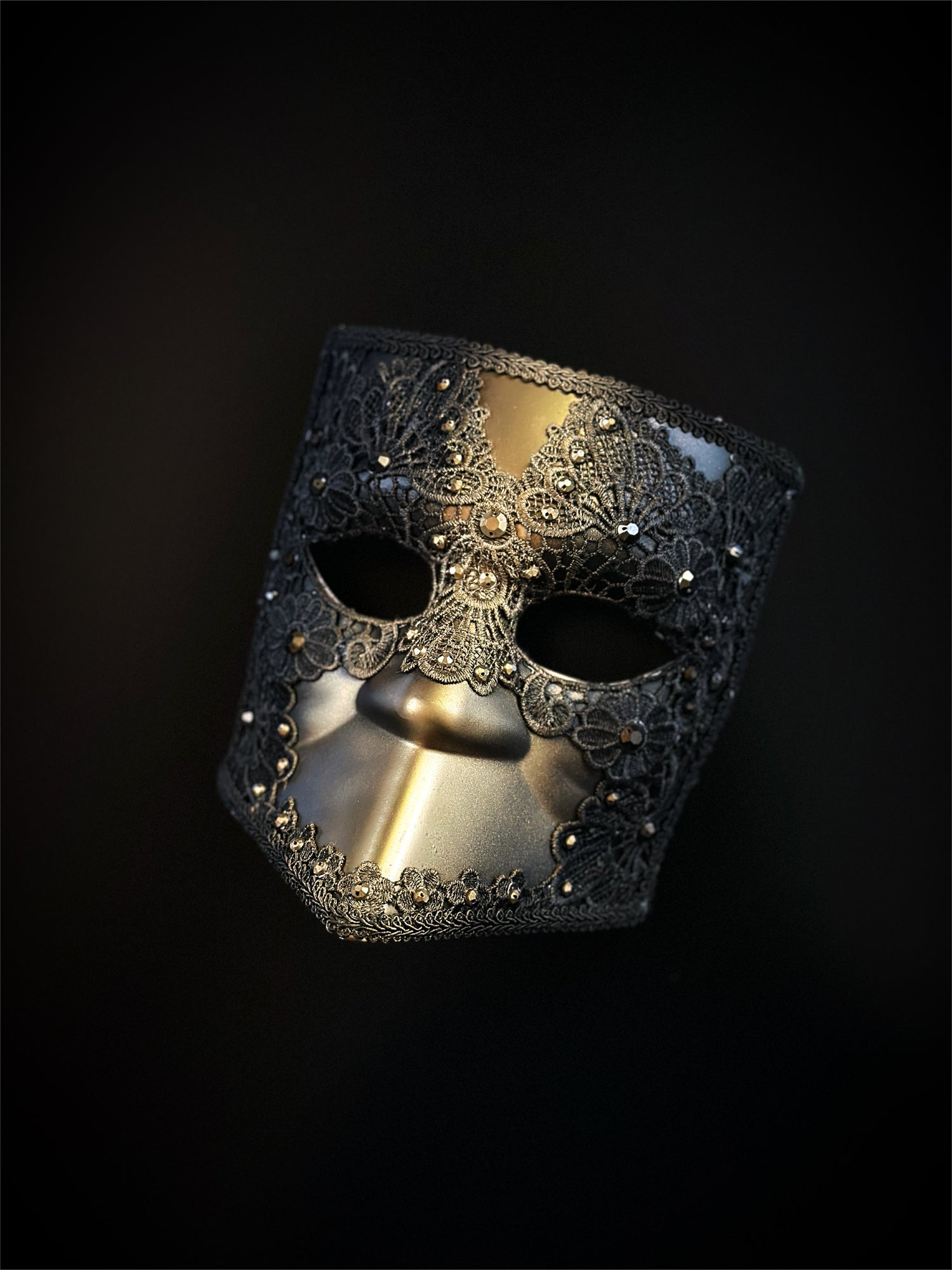 Venetian Bauta mask in gold and black with ornate lace overlay and crystal accents for an elegant, mysterious look.

