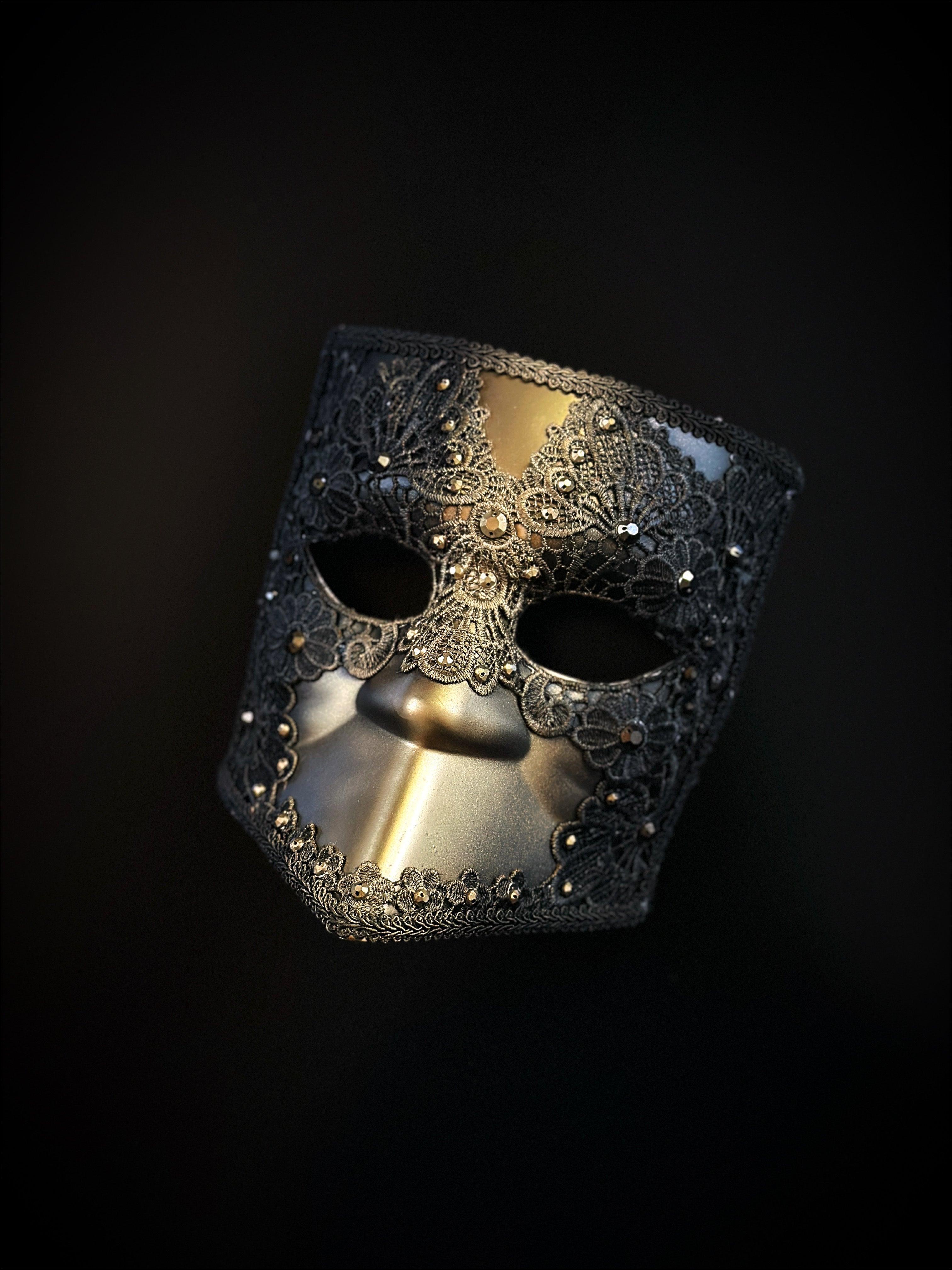 Venetian Bauta mask in gold and black with ornate lace overlay and crystal accents for an elegant, mysterious look.
