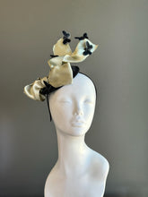 Champagne colored satin ribbon fascinator hat with black butterfly accents for weddings and cocktail events.