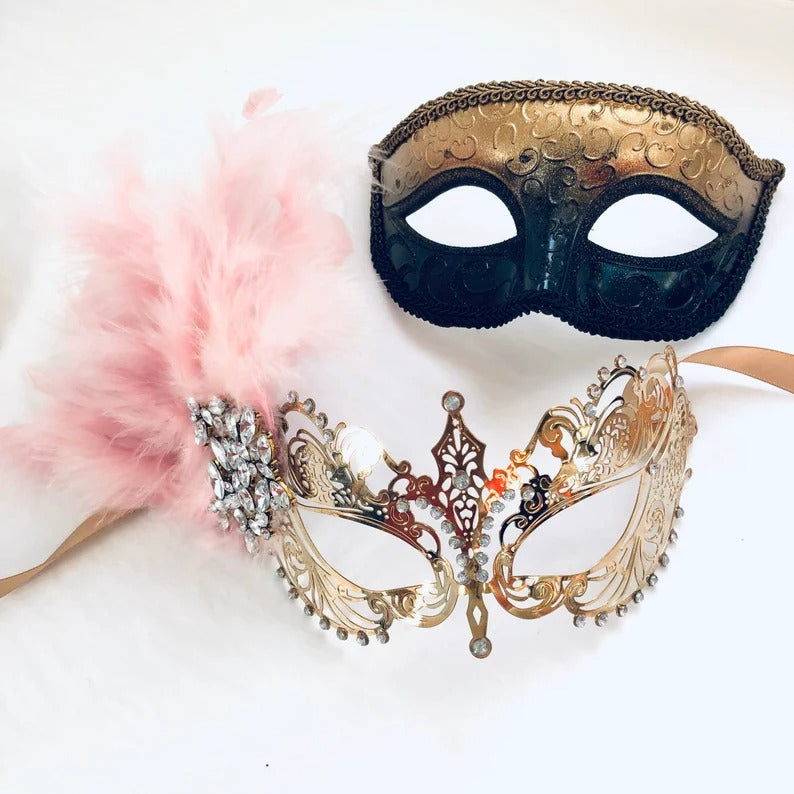 Gold and black men’s mask with matching girl’s gold filigree pink feather masquerade mask.