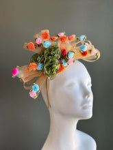 Pastel floral sinamay fascinator with ribbon roses and mesh loops for derby and wedding occasions.