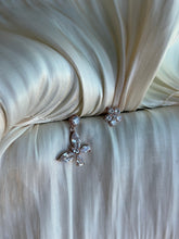 Rose gold butterfly and flower earrings on ivory satin fabric