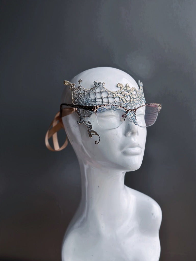 French blue and gold lace mask designed for eyeglass wearers on a white mannequin head