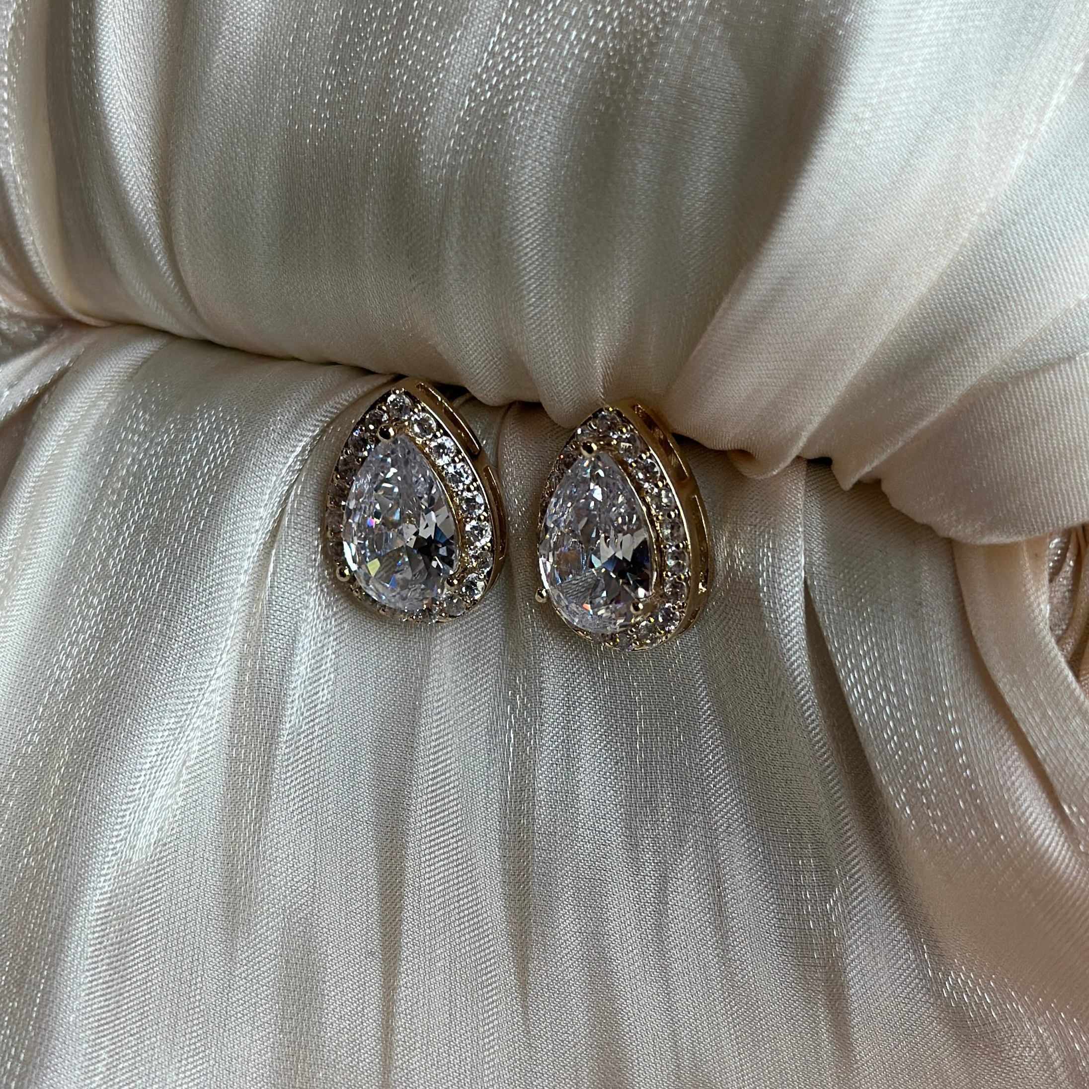 Gold earrings with teardrop-cut crystals encased in a double halo of shimmering stones.