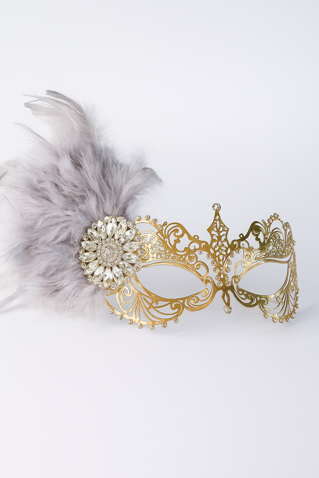 Elegant gold filigree mask with crystal accents and grey feathers, ideal for masquerade balls, weddings, or prom.