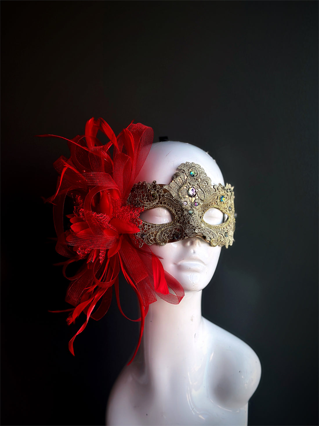 Gold masquerade mask for women with red ribbon flower and tulle embellishment.