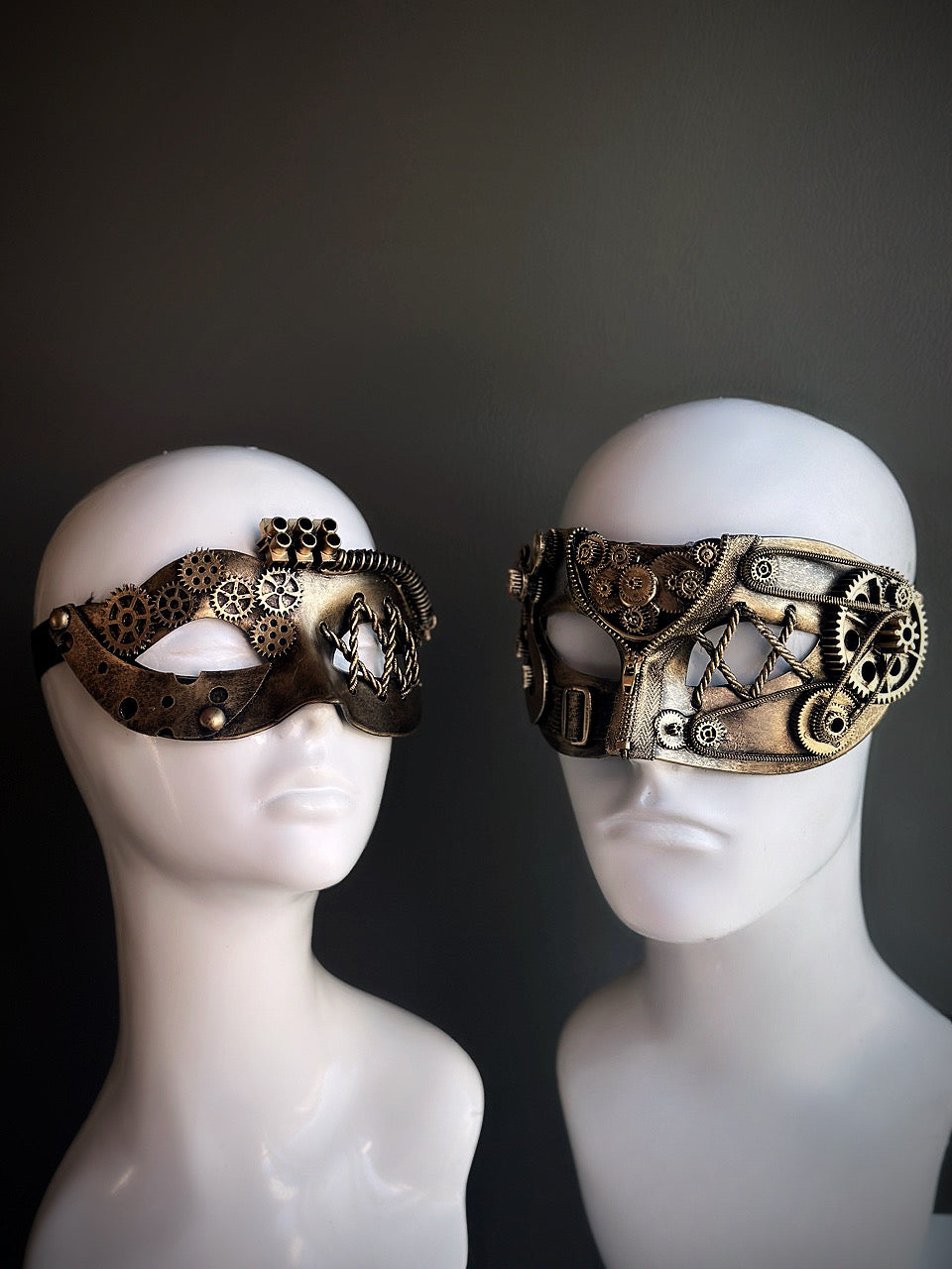 Gold steampunk couples masquerade mask set with intricate gear detailing and mechanical accents, displayed on mannequin heads.