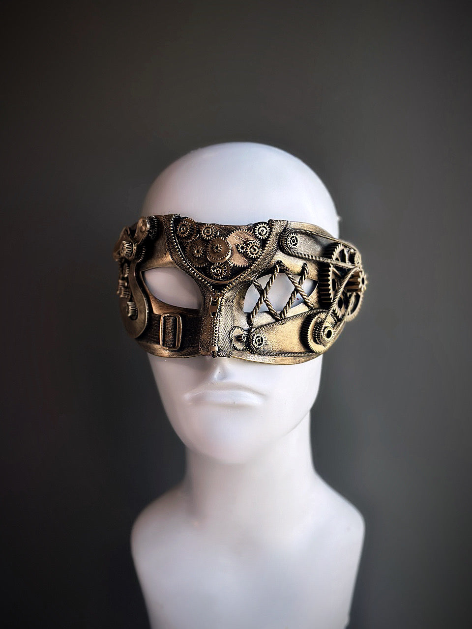 Gold steampunk masquerade mask with detailed gears and industrial accents displayed on a mannequin head.


