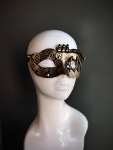 Gold steampunk masquerade mask for women with intricate gear detailing and metallic accents, displayed on a mannequin head.

