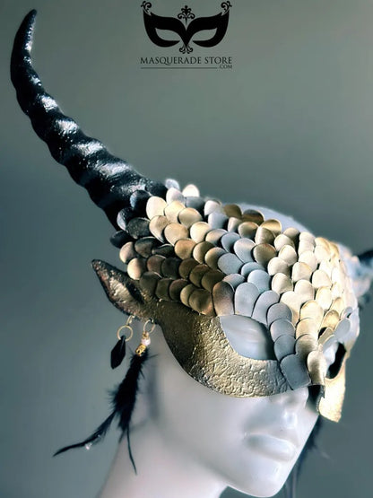 Fantasy dragon horn masquerade mask in gold with scales, black horns, and feather accents, designed as a dramatic headdress.