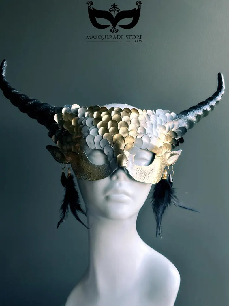 Fantasy dragon horn masquerade mask in gold with scales, black horns, and feather accents, designed as a dramatic headdress.