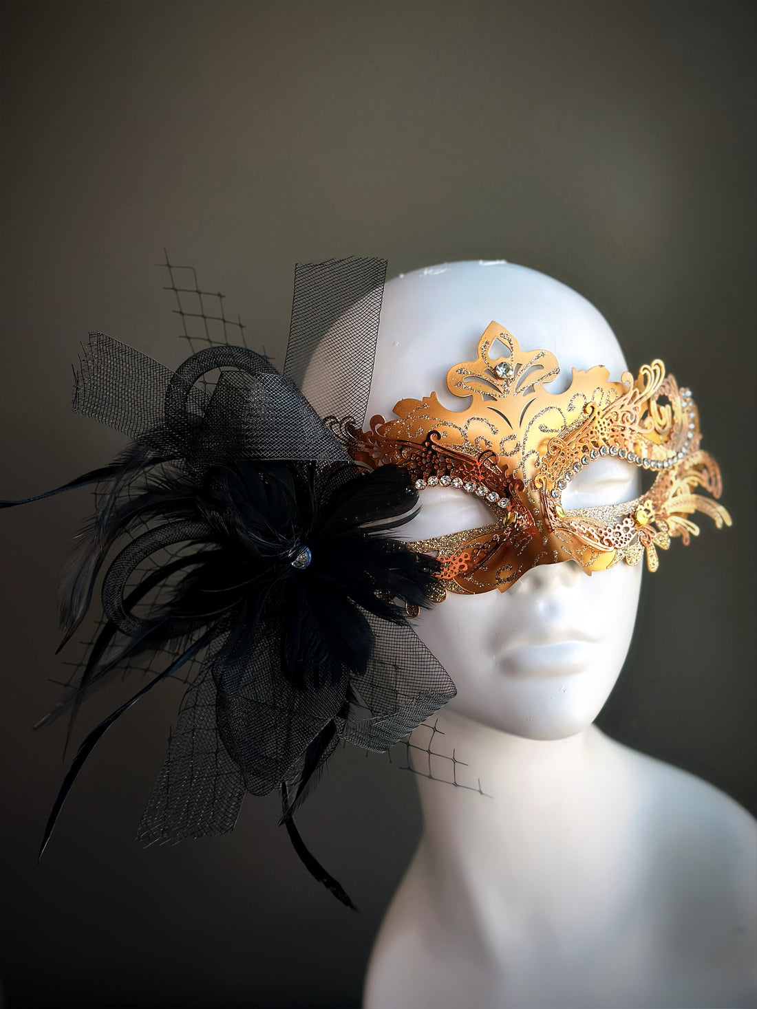 Gold filigree masquerade mask for women with black flower, feathers, and tulle detail.