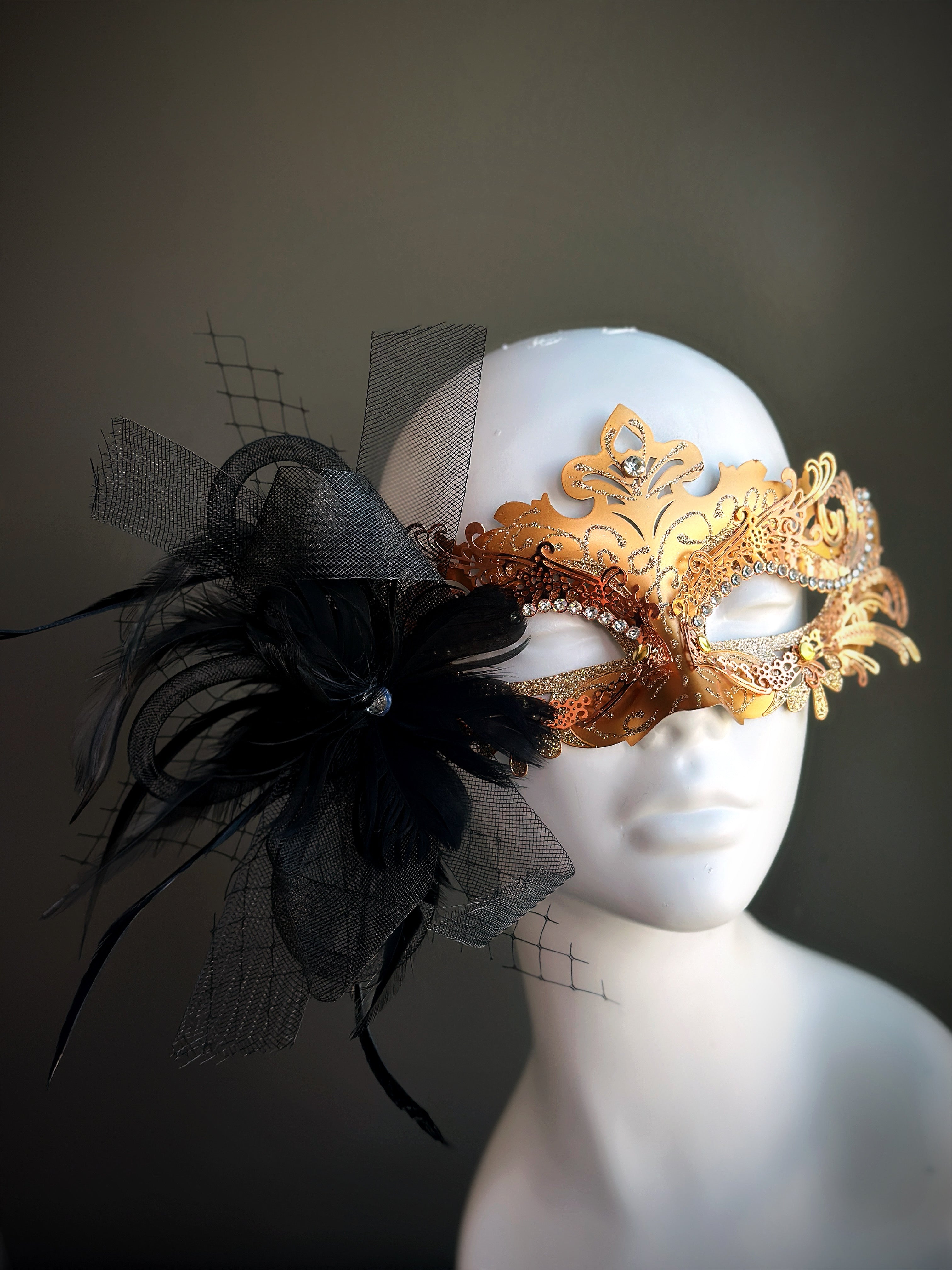 Gold masquerade mask with black feathers and rhinestones for elegant events