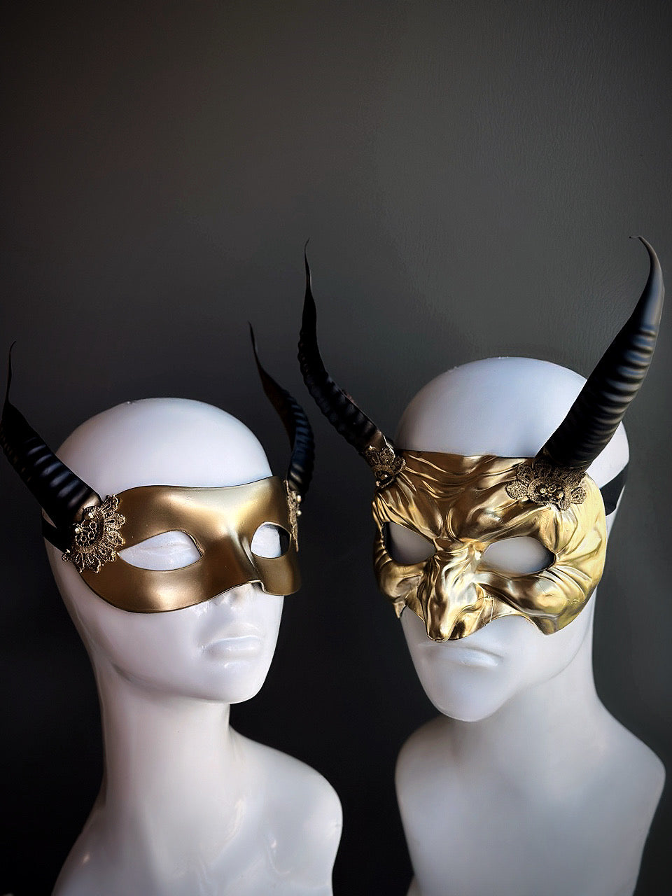 Golden and black horned couple masks with intricate sculpted details and ornate embellishments,
