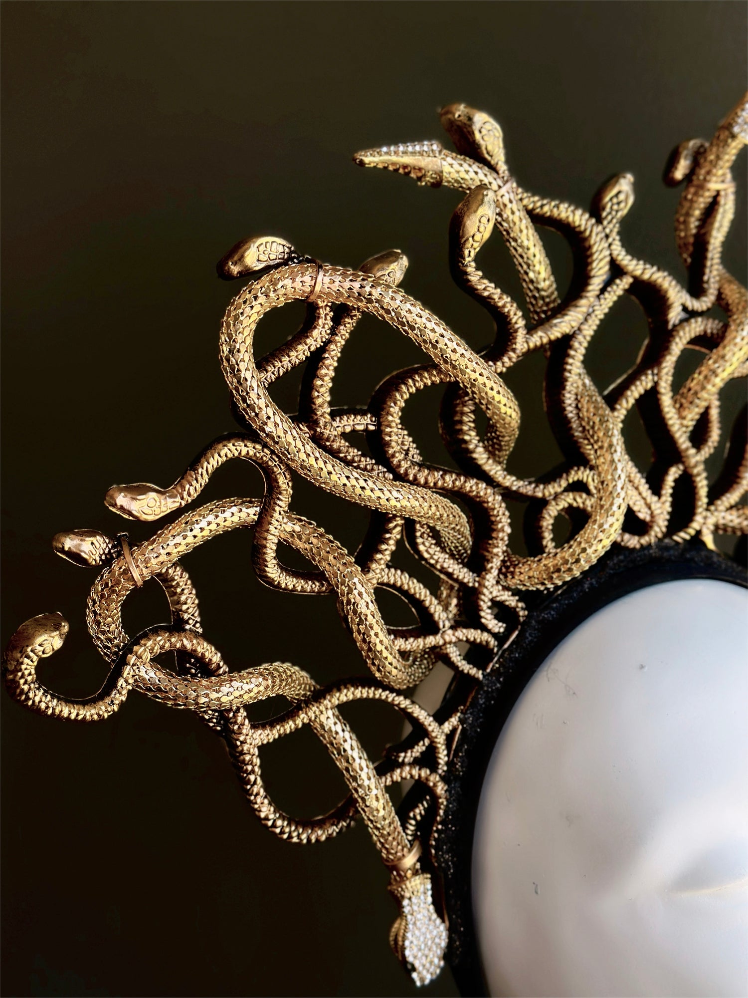 Side view of goddess Medusa crown headpiece adorned with curling gold serpents for dramatic effect
