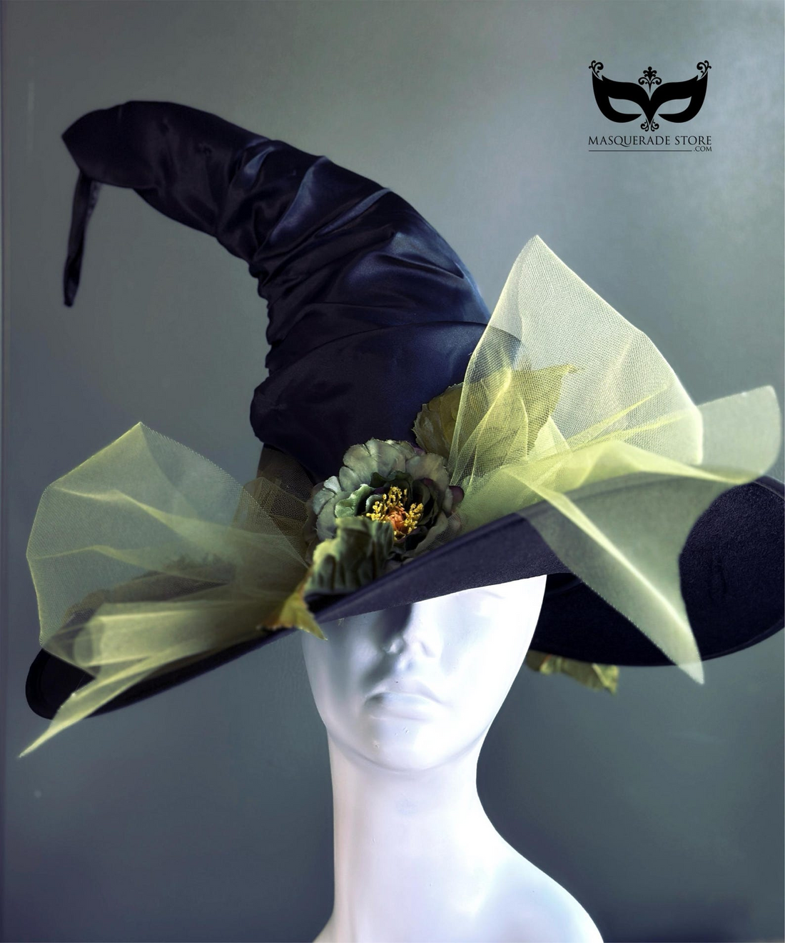 Curled black witch hat with green tulle, leaves, and green flower accents for costume or Halloween look