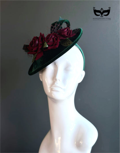 Green velvet fascinator hat with red floral accents.