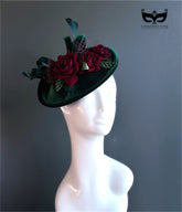 Green velvet fascinator hat with red floral accents.