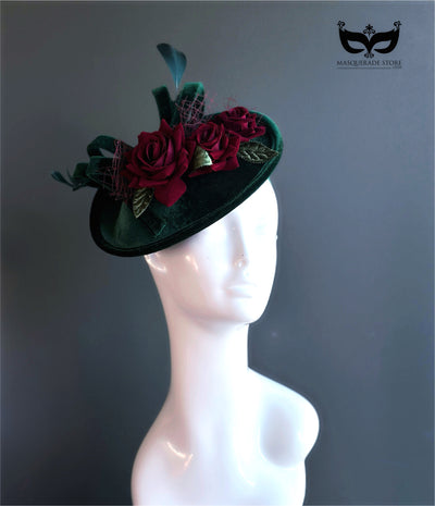 Green velvet fascinator hat with red floral accents.