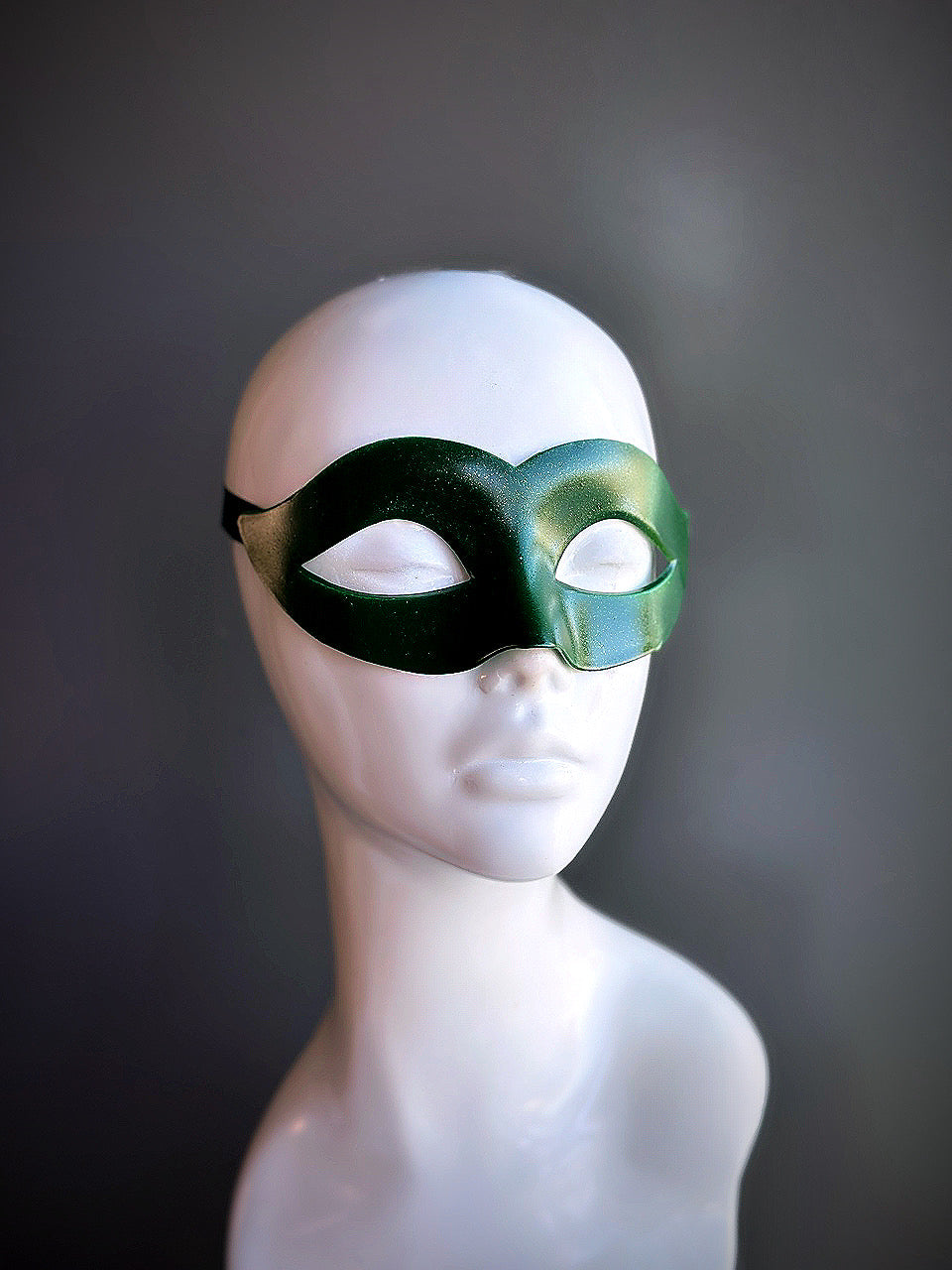 Elegant green Venetian eye mask with a smooth finish, displayed on a mannequin.

