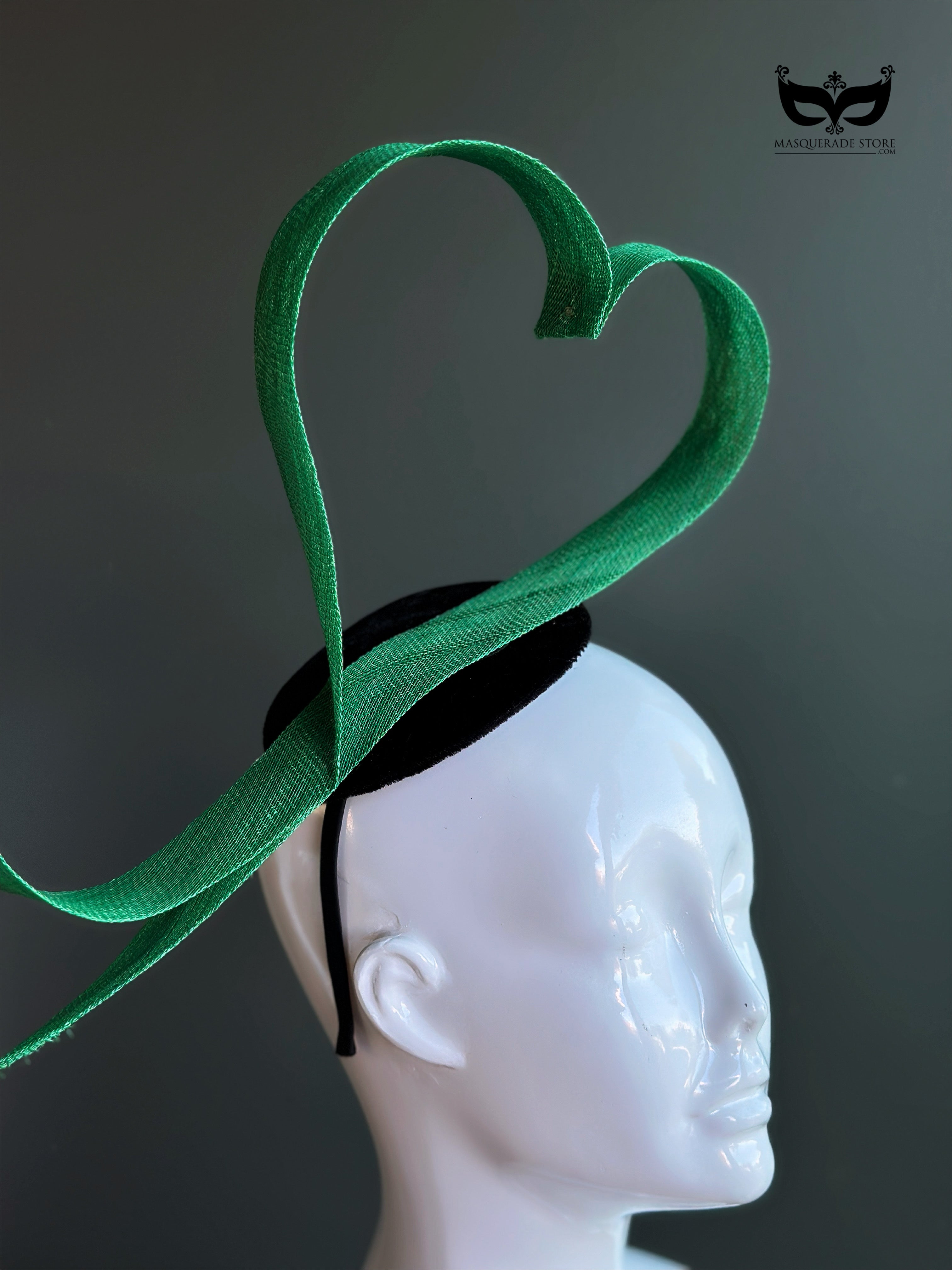 Green heart loop fascinator headband with sculptural ribbon design on mannequin