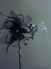 Handheld black masquerade mask with black feathers and rhinestone accents

