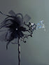 Handheld black masquerade mask with black feathers and rhinestone accents

