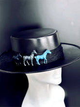 Black wide-brim hat with three horses in blue, gray, and black.
